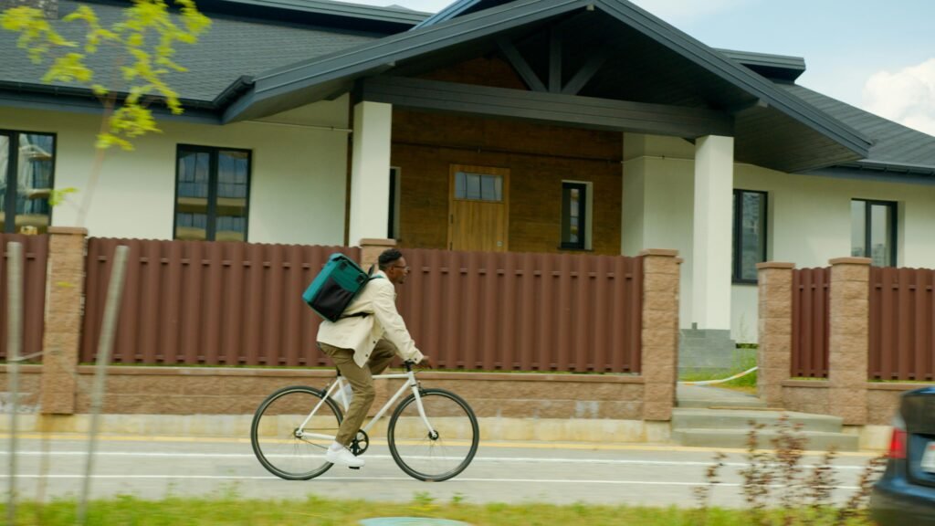 A courier rides a bike for delivery work through a neighborhood street.
